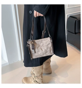 Detailed view of a beige quilted crossbody bag with brown leather trim and silver clasp