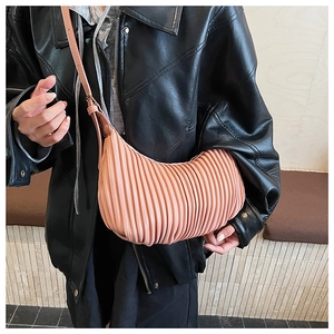 Detail of light orange pleated crescent bag with vertical textures and leather strap