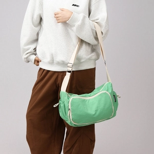 Close-up of light green leisure crossbody bag with adjustable wide strap and side drawstring