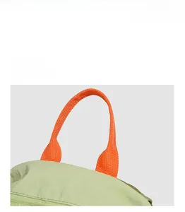 Detail of orange woven handle and light green wrinkled nylon fabric with zipper