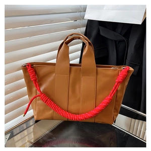 Dettaglio di una borsa tote marrone con tracolla in corda intrecciata rossa spessa