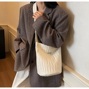Detailed view of cream pleated shoulder bag with LOVE label and soft fabric texture