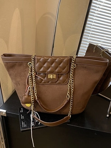 Brown suede tote bag with quilted chain strap and gold hardware in minimalist setting