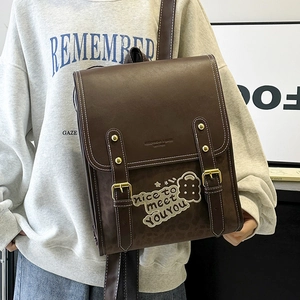 Detail of retro brown leather backpack featuring teddy bear embroidery and gold studs