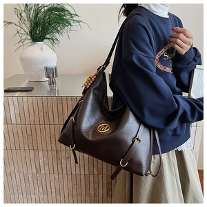 Détail d'un sac à bandoulière marron foncé vintage avec logo M doré et perles en bois