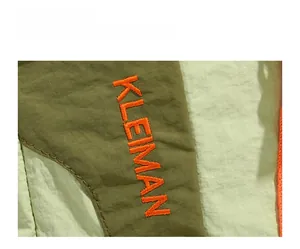 Macro detail of Kleman orange embroidery on lightweight olive nylon travel backpack