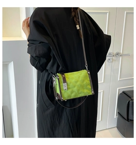 Detail of green quilted crossbody bag with brown leather trim and silver metal lock
