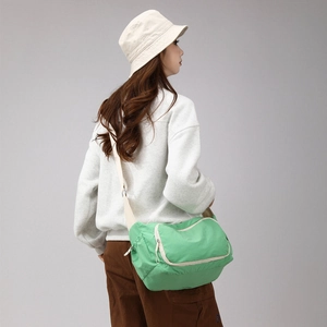 Side view of fruit green crossbody bag with multiple zippers and beige nylon strap