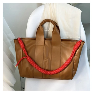 Dettaglio della borsa tote color caramello in ecopelle con decorazione in corda rossa