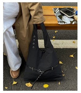 Detail view of black nylon tote bag featuring wide shoulder strap and metal buckle belt