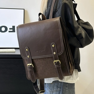 Side view of dark brown vintage faux leather backpack with white stitching and buckles