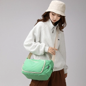 Detail of mint green crossbody bag with white piping zipper shown on casual streetwear model