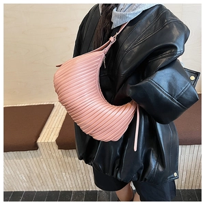 Detail of pink pleated hobo bag worn by model with adjustable strap and crescent shape