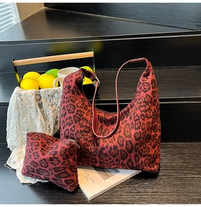 Detail of red leopard print hobo bag set with matching pouch on a wooden step