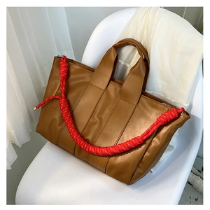 Dettaglio borsa tote marrone caramello con tracolla a corda intrecciata rossa e bianca