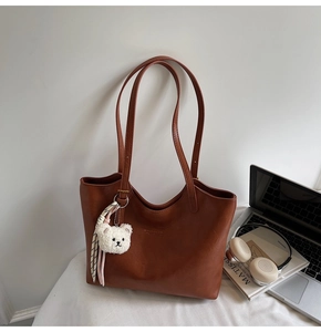 Detailed shot of retro brown tote bag with plush bear charm and ribbon accessory