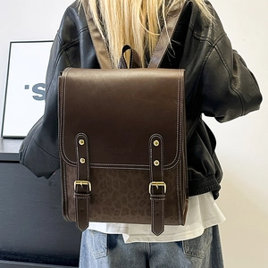 Detail of vintage brown leather backpack with leopard print flap and gold buckles on a model