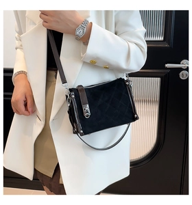 Close-up of black quilted suede handbag with brown leather trim and silver buckle
