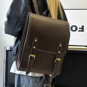 Detailed side view of dark brown PU leather backpack with gold buckles and leopard print base