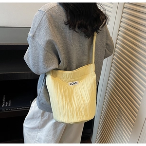 Detail showing light yellow wrinkled bucket bag with LOVE patch on a female model