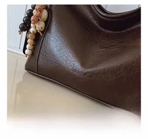 Detailansicht der braunen Leder-Umhängetasche mit Vintage-Perlenanhänger im Retro-Stil