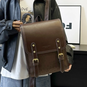 Detailed view of dark brown vintage leather backpack with gold buckles and white stitching