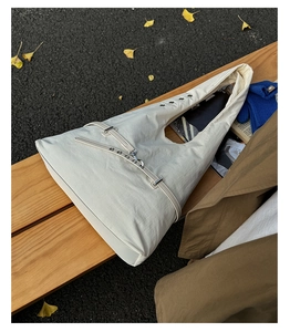 Detail of a beige canvas tote bag with metal eyelets on a wooden bench with autumn leaves