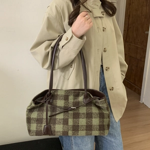 Detail of green and brown checkered tote bag with leather handles shown on a model
