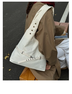Detail of off-white tote bag with metal eyelets and adjustable strap in autumn setting