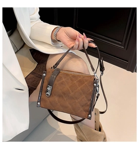 Detail of brown quilted crossbody bag with frosted texture and silver twist lock