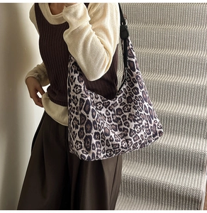 Close-up of leopard print tote bag with wide black shoulder strap and zipper closure