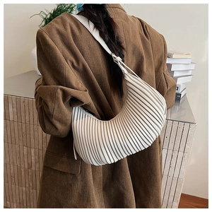 Detail showing vertical pleated texture of creamy hobo bag with adjustable strap
