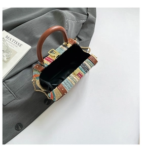 Detailed view of colorful woven bag featuring brown leather handle and gold chain strap