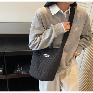 Detail of black pleated bucket bag featuring LOVE woven label on casual outfit
