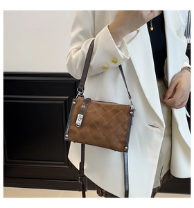 Detail showing brown quilted crossbody bag with silver twist lock and contrast stitching