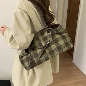Detail of green brown plaid tote bag in textured tweed with slim leather straps