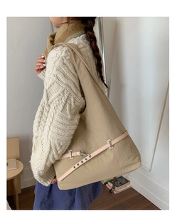Close-up of a large khaki fabric shoulder bag with leather strap and metal buckle detail