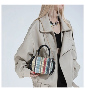 Detail of colorful woven handbag with gold rivets and metallic chain strap on model