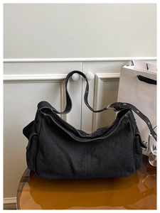 Detailed view of black denim crossbody bag featuring side cargo pockets and adjustable strap