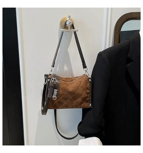 Detail of brown quilted suede crossbody bag showing diamond stitching and leather corners