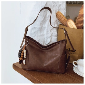 Detailansicht braune Ledertasche mit Retro-Perlen und Mojo Bags-Logo auf Holzoberfläche