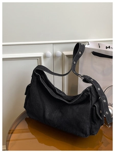Close-up of black denim bag with silver eyelets and adjustable buckle strap detail