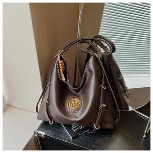 Détail du sac Hobo marron foncé avec logo M doré et pompon rétro en perles de bois
