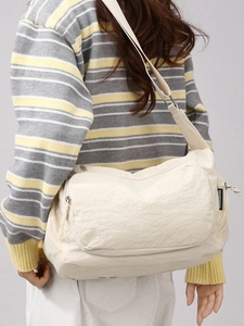 Minimalist beige lightweight nylon crossbody travel bag for women worn over the shoulder