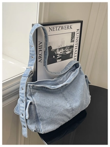 Detail of light blue denim hobo bag with eyelet strap and side pocket design