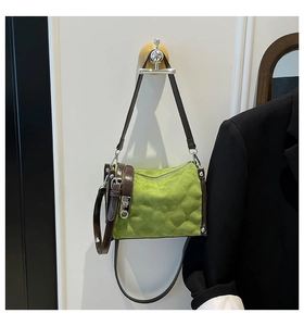 Detailed view of green quilted suede bag with brown leather trim and silver clasp