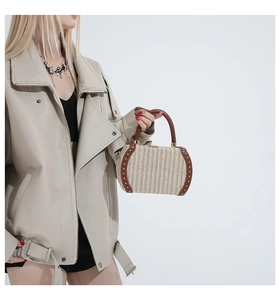 Detail of a woven rainbow box bag featuring brown leather trim and golden rivets