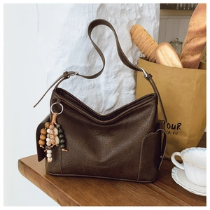 Detail der braunen Retro-Ledertasche mit buntem Boho-Anhänger und silberner Schnalle