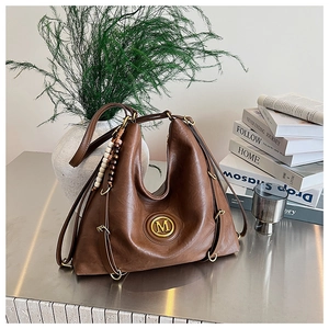 Détail du sac cabas en cuir marron vintage avec logo M doré et charme bohème