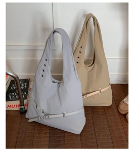 Detail of light gray and beige nylon tote bags with metal eyelets and decorative belts